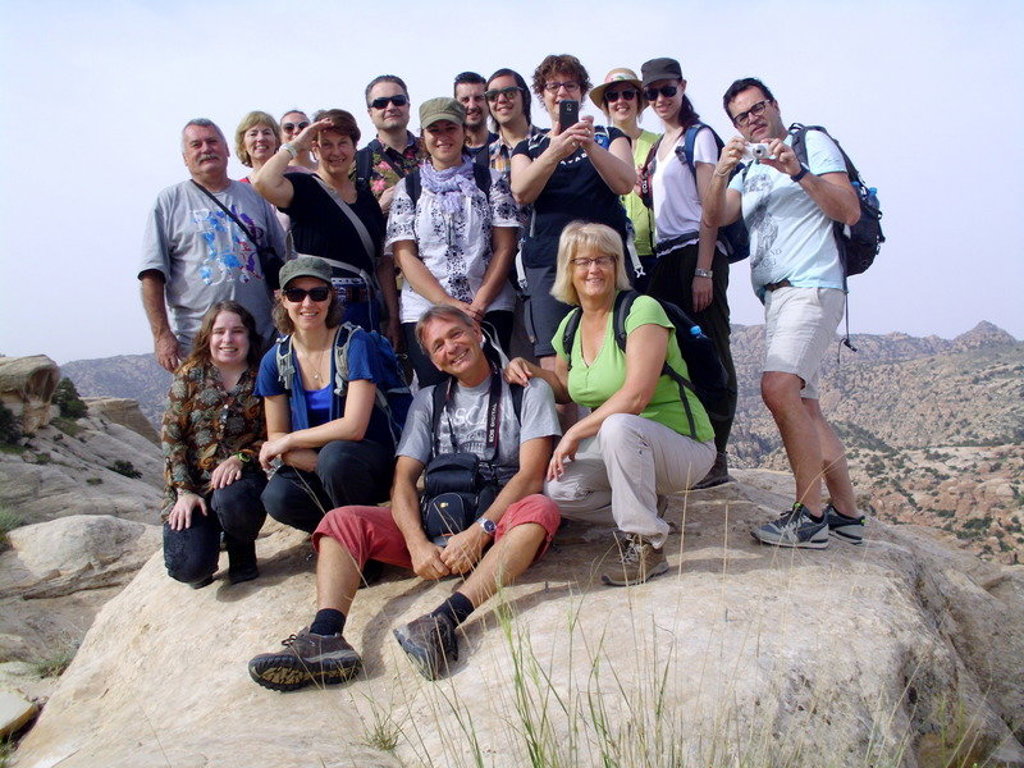 Groepsrondreis Jordanië: reizigers poseren op rotsen met berglandschap op de achtergrond.