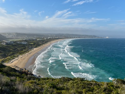 Kustlijn van Zuid-Afrika met lang zandstrand en golven, gezien vanaf een uitkijkpunt.