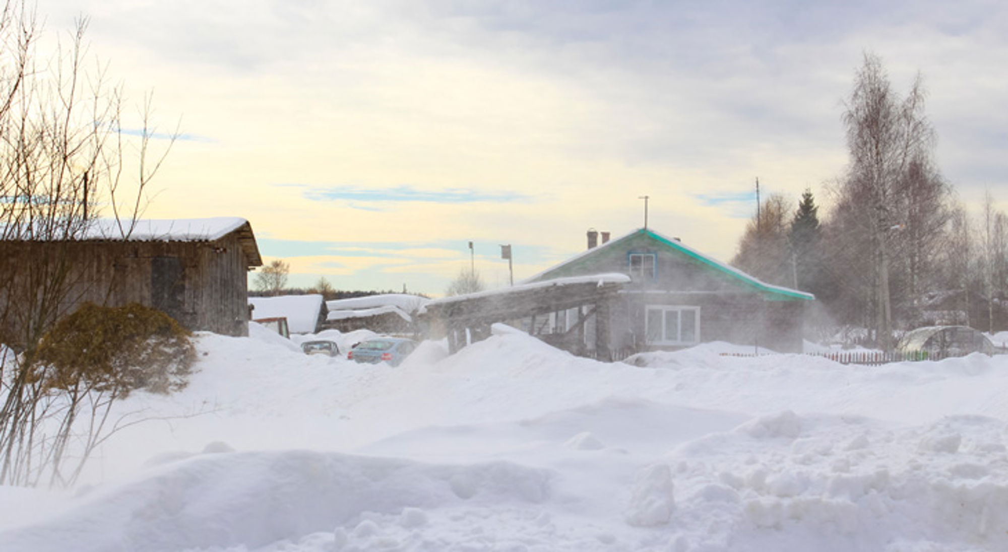 winterlandschap Rusland Sneeuwrijk dorp met houten huizen en opwaaiende sneeuw bij winterweer.