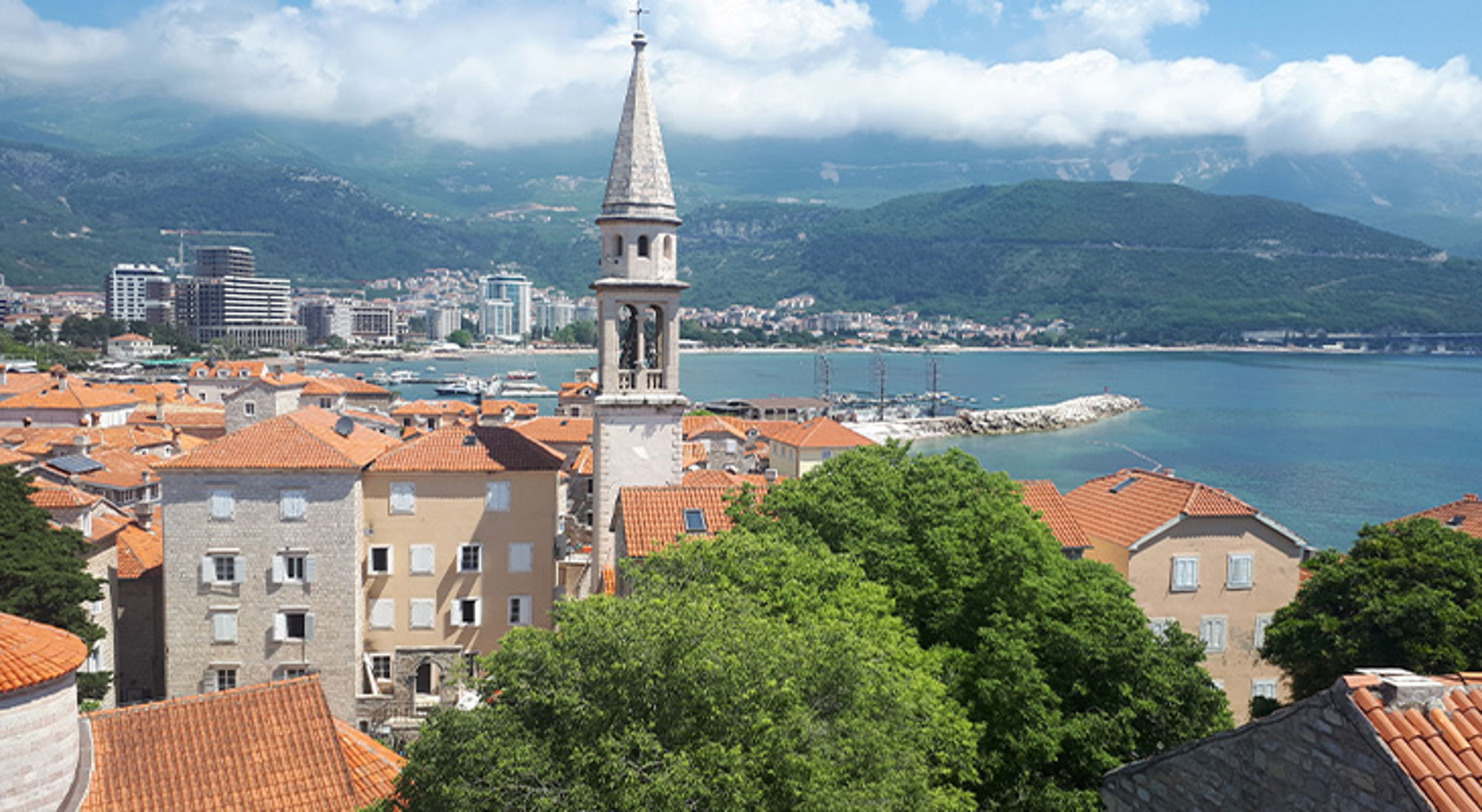Balkan Uitzicht op de oude stad Budva met kerktoren, rode daken en de Adriatische Zee op de achtergrond.