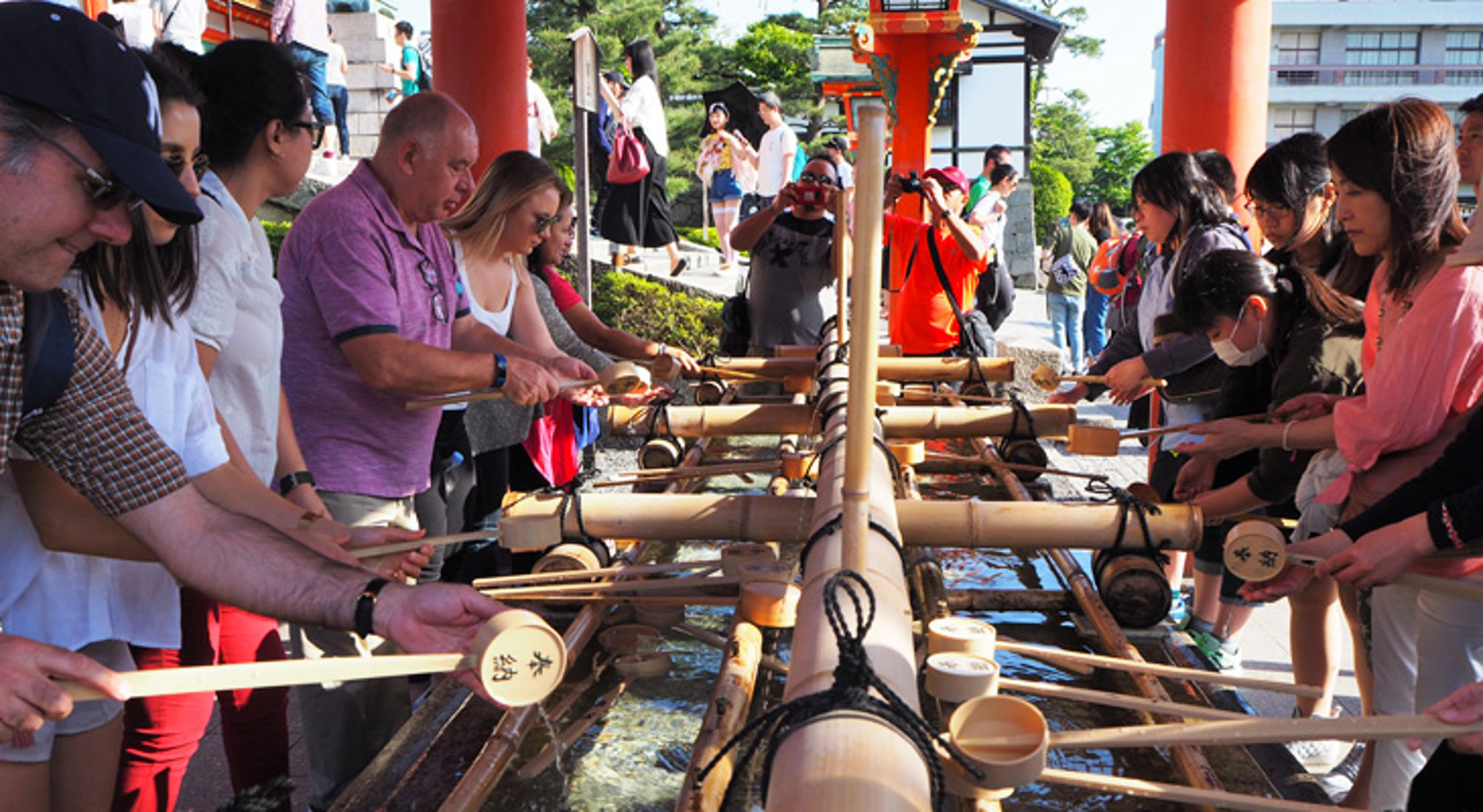 Bezoekers wassen handen bij het temizuya-reinigingsritueel in een Japanse tempel.
