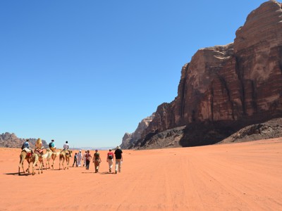 Groep reizigers te voet en op kamelen in de Wadi Rum-woestijn, Jordanië.