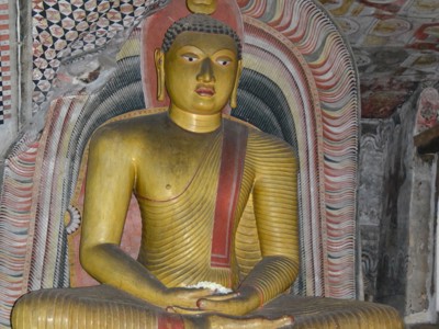 Gouden Boeddhabeeld in een grot, met kleurrijke muurschilderingen in een tempel op Sri Lanka.