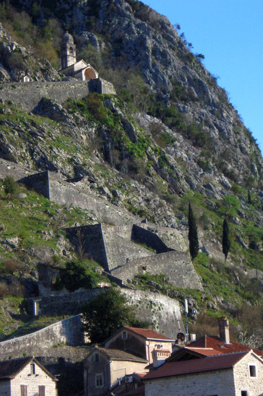 Kerkje en vestingmuur op de berghelling bij Kotor, Montenegro.