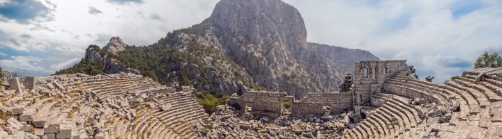 Antiek theater van Termessos met stenen tribunes en ruïnes, met berglandschap op de achtergrond.