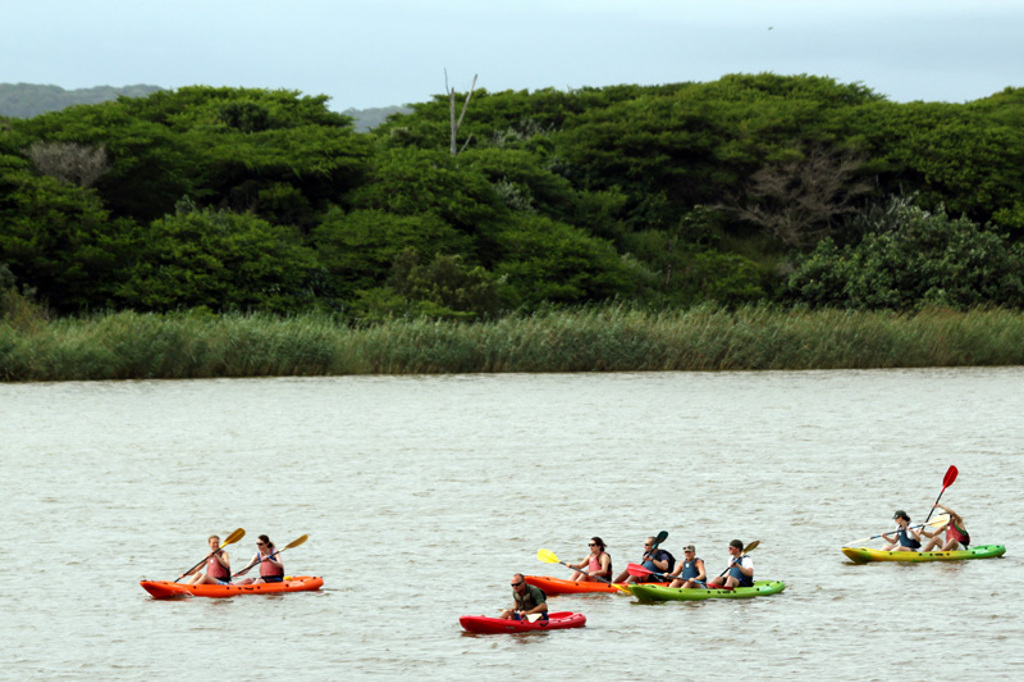 Groep reizigers kajakt op een brede rivier tijdens een kampeerreis in Zuid-Afrika.