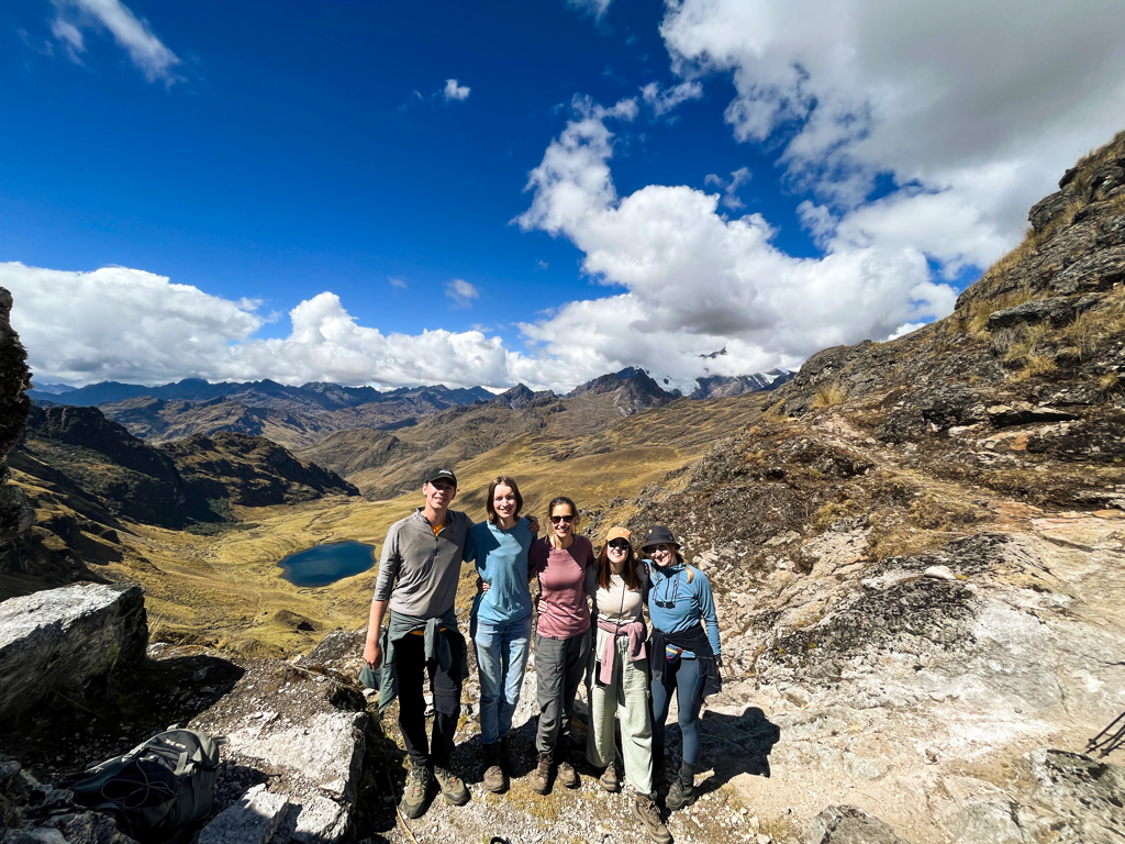 Jonge reizigers tijdens een 22-35ers groepsrondreis Peru met uitzicht op Andesbergen en een bergmeer.