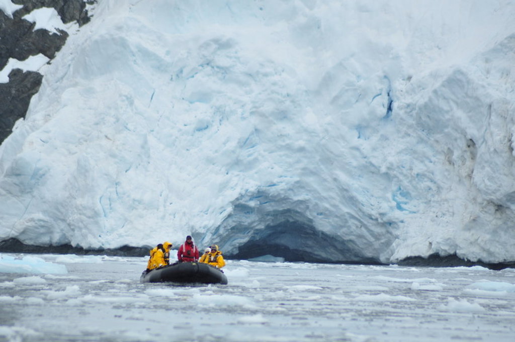 Zodiacboot met reizigers voor een ijsgrot in Antarctica tijdens de groepsrondreis Crossing the Circle.
