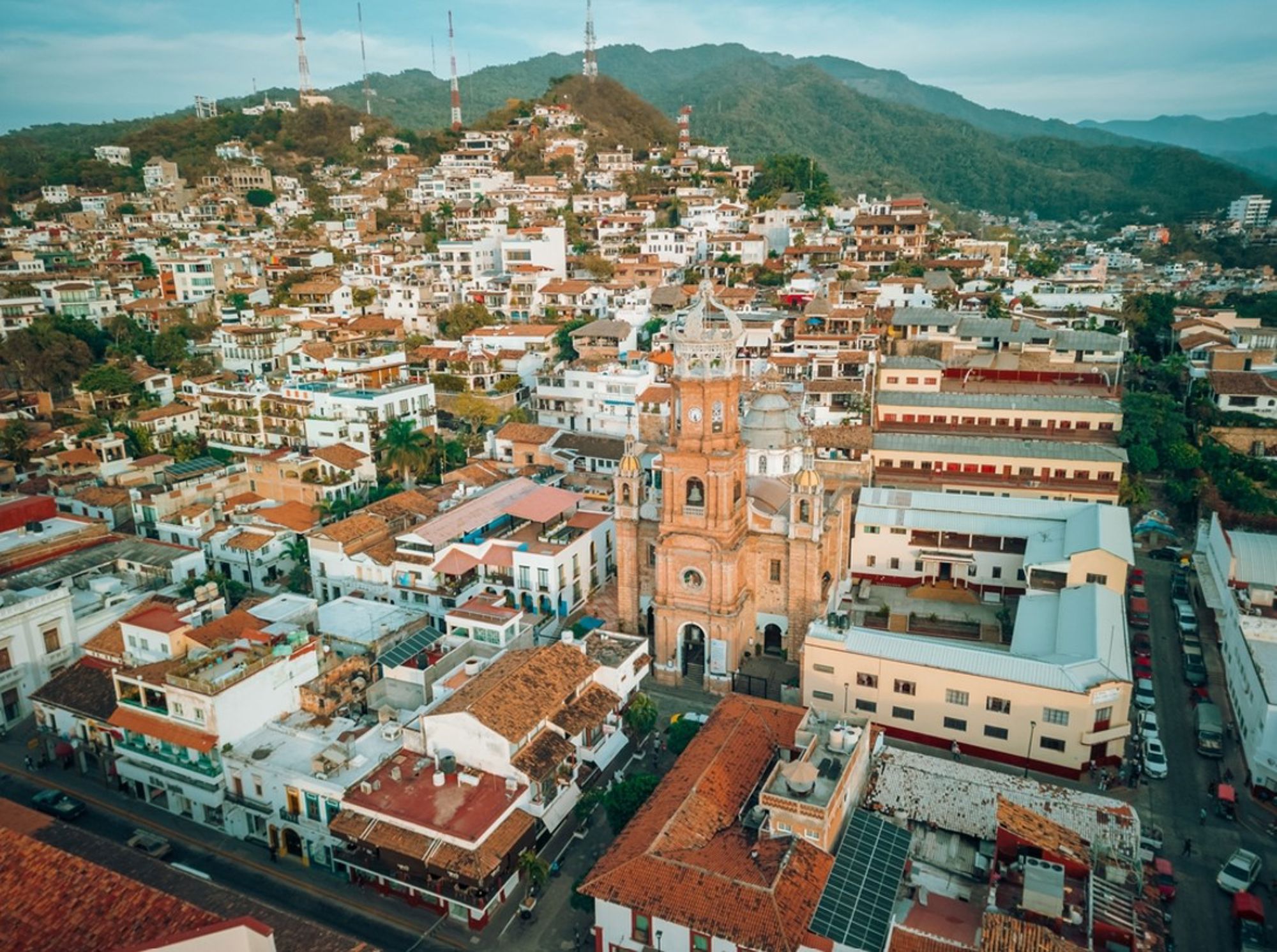 Uitzicht op de Parroquia de Nuestra Señora de Guadalupe in Puerto Vallarta, met de stad en bergen op de achtergrond.