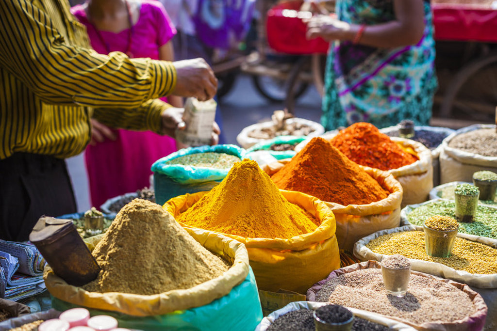Kruidenmarkt in Noord-India met kleurrijke specerijen in zakken en bezoekers bij de kraam.