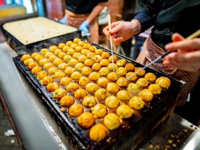 Verse takoyaki-balletjes worden op een bakplaat gedraaid met stokjes op een Japanse foodmarkt.