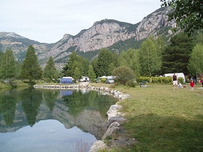 Camping aan een bergmeer in het Parc national des Écrins, met tenten en bergen op de achtergrond.