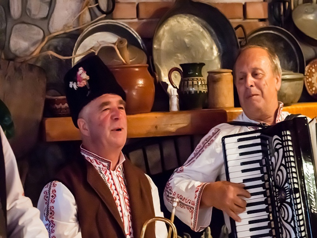 Bulgaarse muzikanten in traditionele klederdracht spelen accordeon tijdens wandelvakantie Bulgarije.