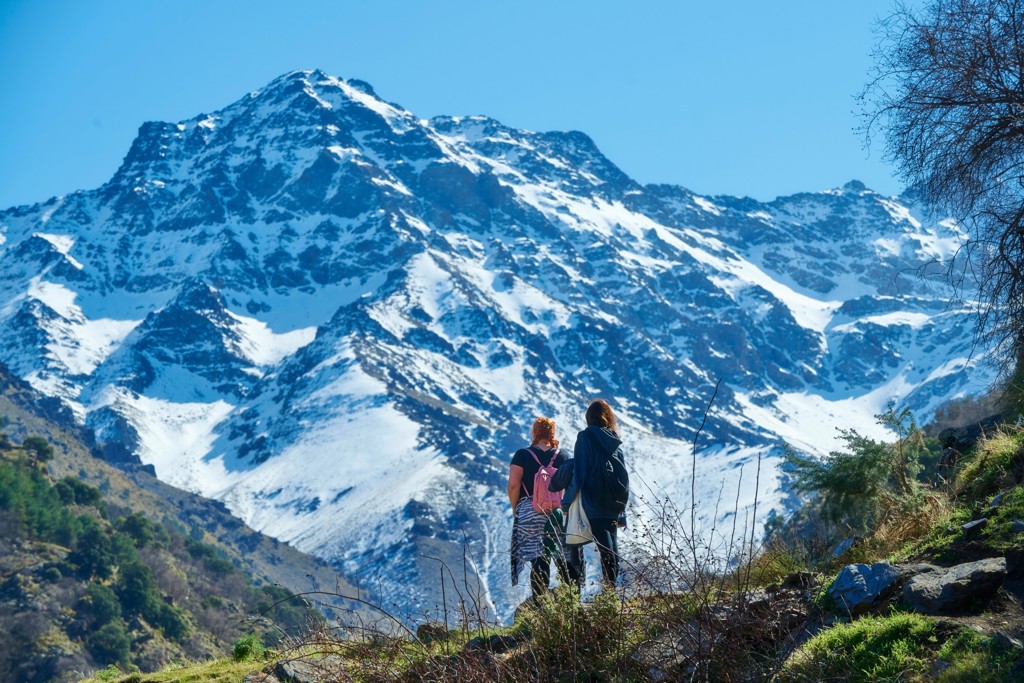 Wandelaars met rugzakken kijken uit op besneeuwde bergen in de Sierra Nevada bij Granada, Spanje.