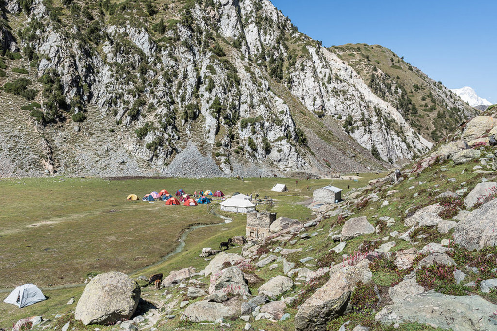 Kamp met kleurrijke tenten in een groene vallei tussen hoge bergen in Baltistan, Pakistan.
