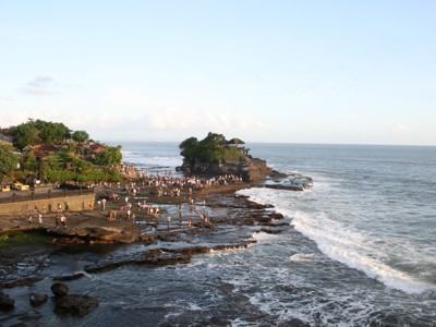 Tanah Lot-tempel op Bali aan de rotskust met bezoekers en golven van de Indische Oceaan.