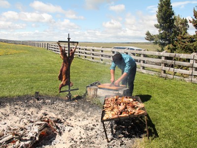 Patagonische asado: man bereidt lamsvlees op open vuur op een estancia, Route Patagonië Hoogtepunten dag 8.