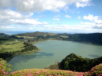 Uitzicht over Lagoa das Furnas op São Miguel, Azoren, met groene heuvels en bloeiende azalea’s.