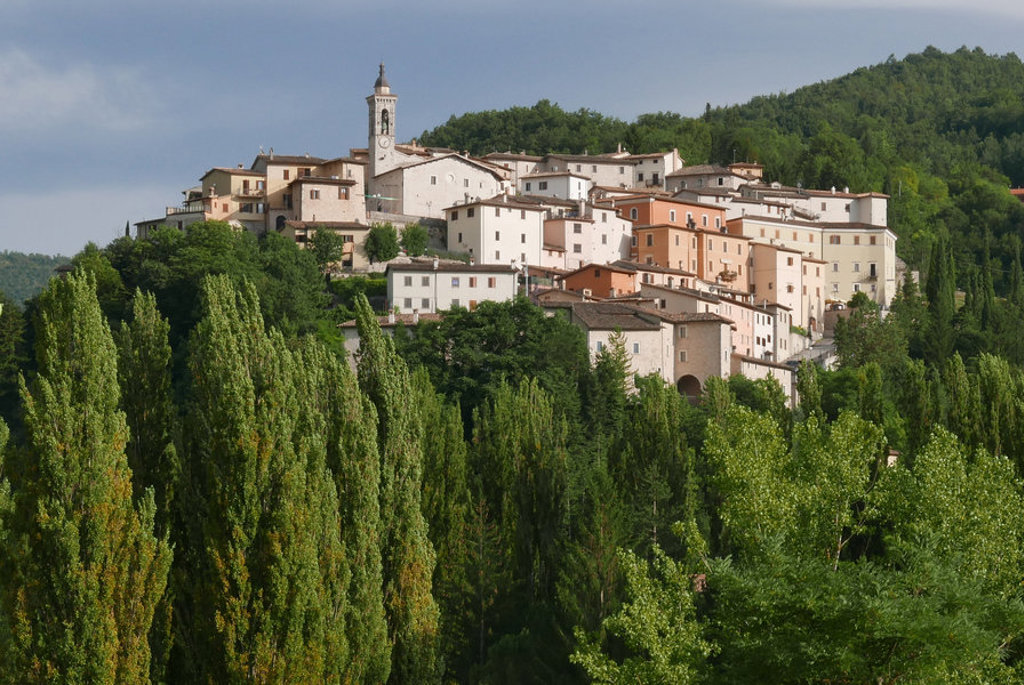 Heuveldorp met kerktoren in de Centrale Apennijnen, Italië, omringd door groene bossen.