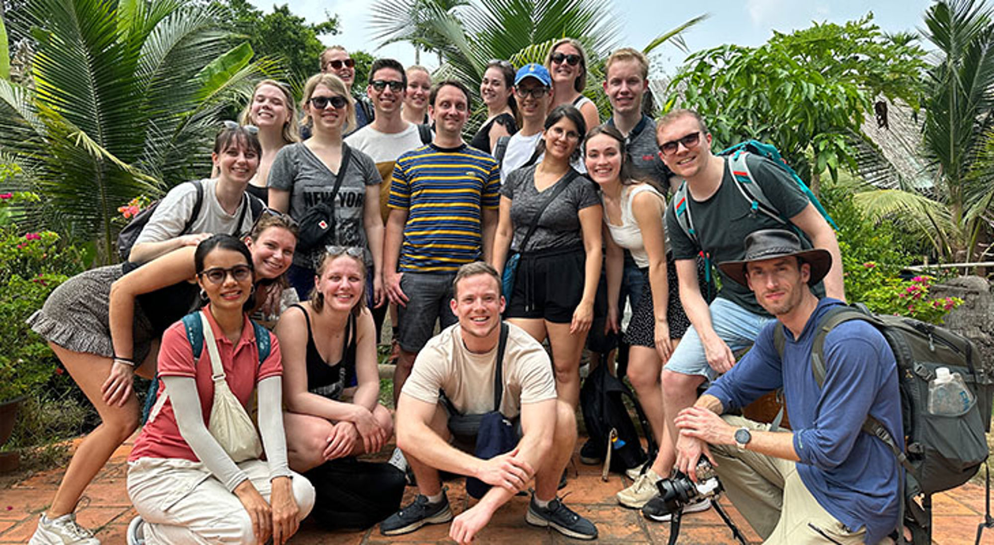 Groepsfoto Vietnam Groepsfoto van reizigers tijdens een excursie in een tropische tuin met palmbomen.