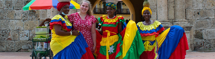 Fleur poseert met vrouwen in kleurrijke jurken op een plein in Colombia.