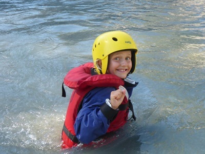 Kind met helm en reddingsvest tijdens wildwateractiviteit in de Écrins, Frankrijk.