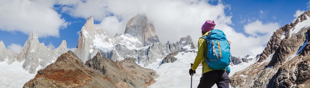 Wandelaar met rugzak kijkt uit op besneeuwde bergtoppen in Patagonië tijdens een groepsrondreis.