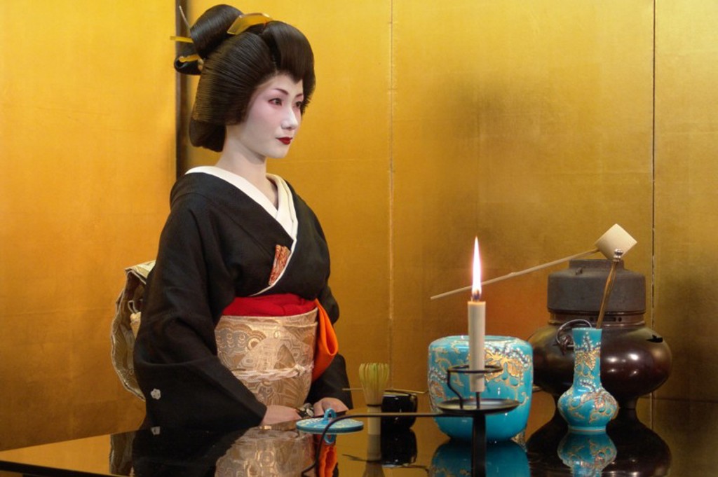 Japanse vrouw in kimono bij theeceremonie met kaars en theeservies, passend bij een familiereis Japan.