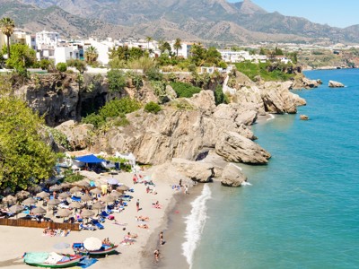 Strand aan de Costa del Sol met rotsen en witte huizen, tijdens de Andalusië familiereis van 9 dagen.