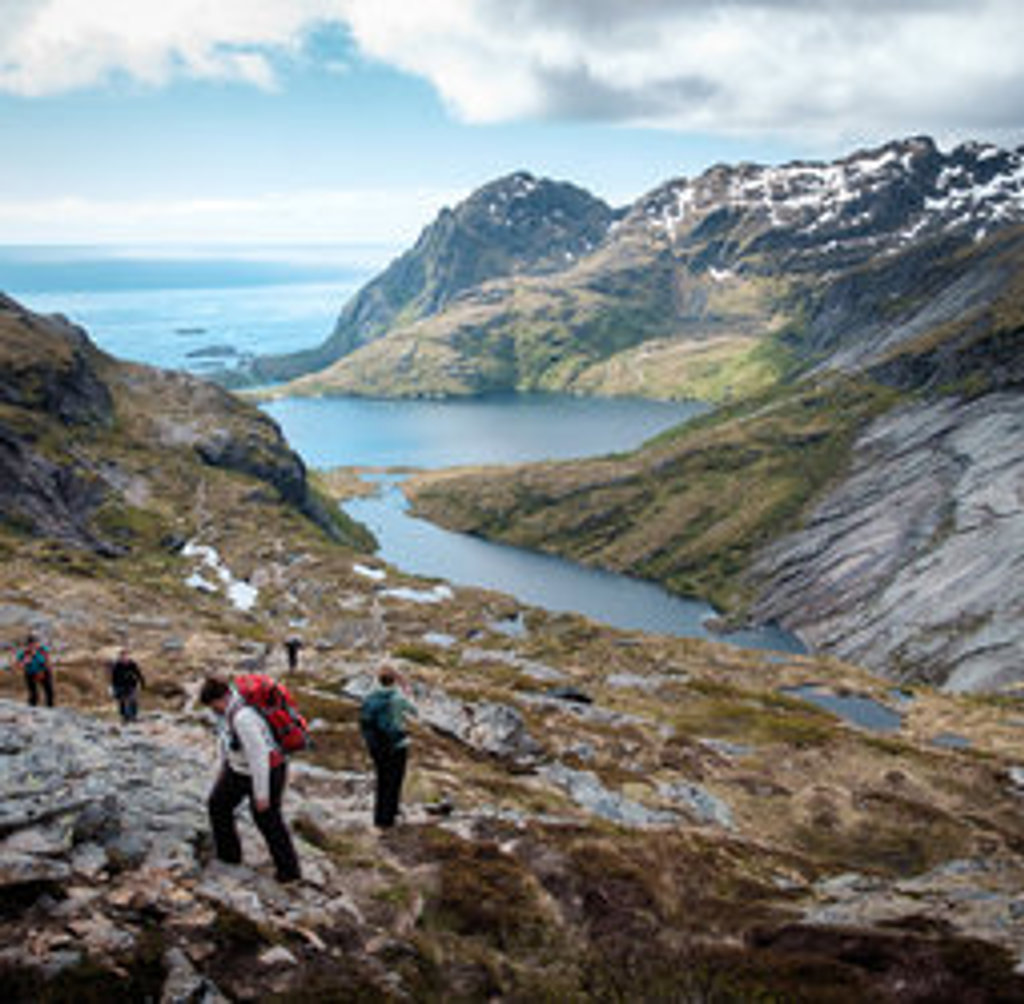 Wandelaars in ruig berglandschap bij een fjord op de Lofoten, Noorwegen.