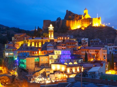 Avondzicht op Tbilisi met verlichte Narikala-fort en kleurrijke huizen, Route Georgië.