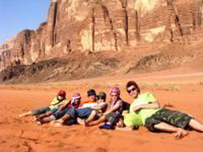 Groep reizigers rust in het rode zand van Wadi Rum tijdens de Route Jordanië.