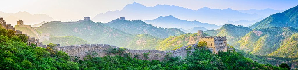 De Chinese Muur slingert over groene bergen, een hoogtepunt tijdens de groepsrondreis Zijderoute met de trein.