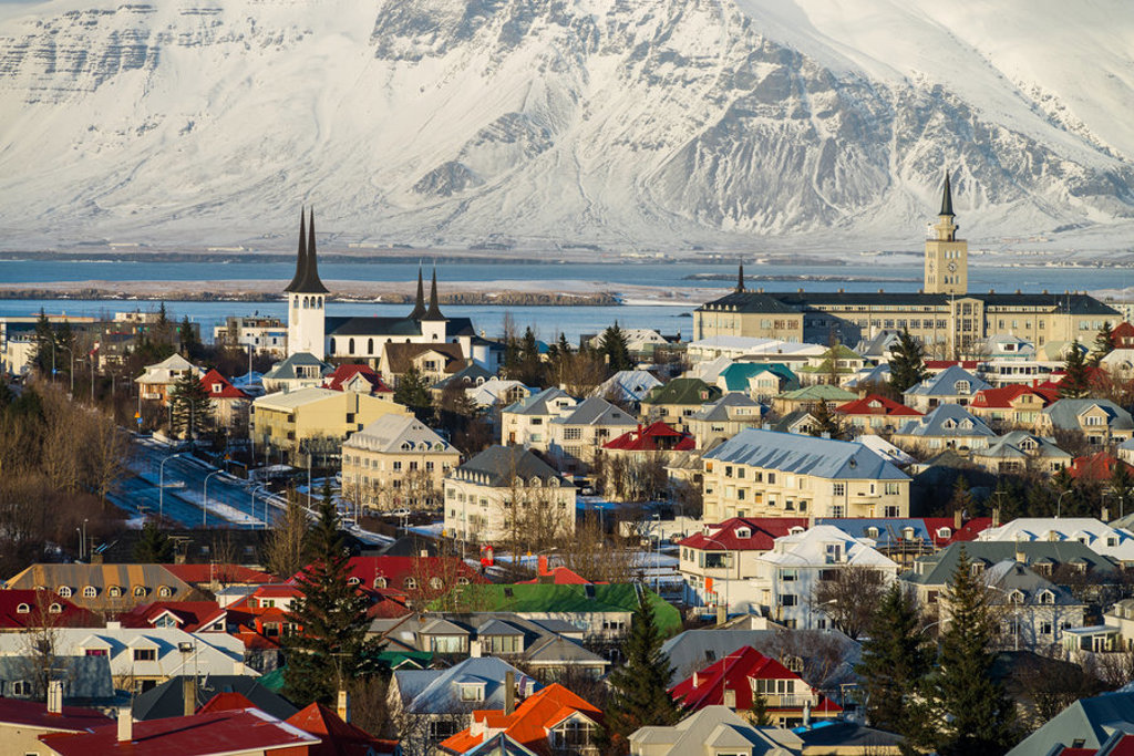 Reykjavik met kleurrijke daken, Hallgrímskirkja en besneeuwde bergen op de achtergrond.