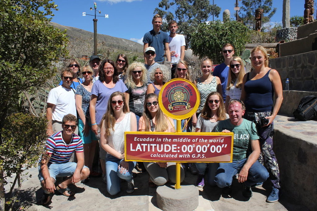Groepsfoto tijdens familiereis Ecuador bij de evenaar, bij het bord “Latitude 0°00'00''” in Mitad del Mundo.