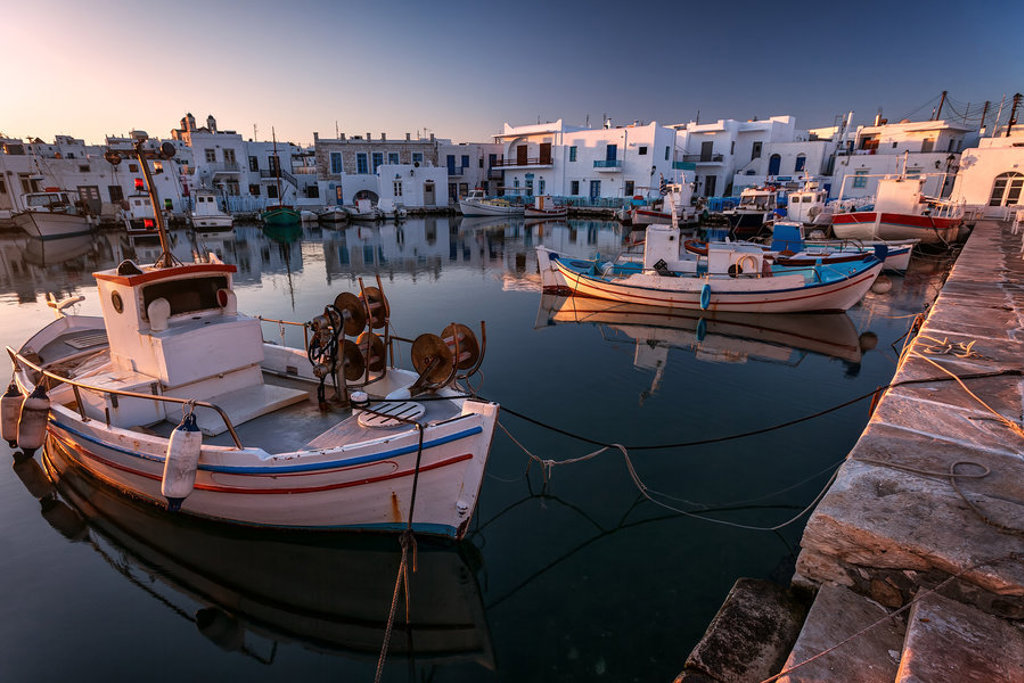 Haven met vissersboten en witte huizen op Naxos, Griekenland, bij zonsondergang.