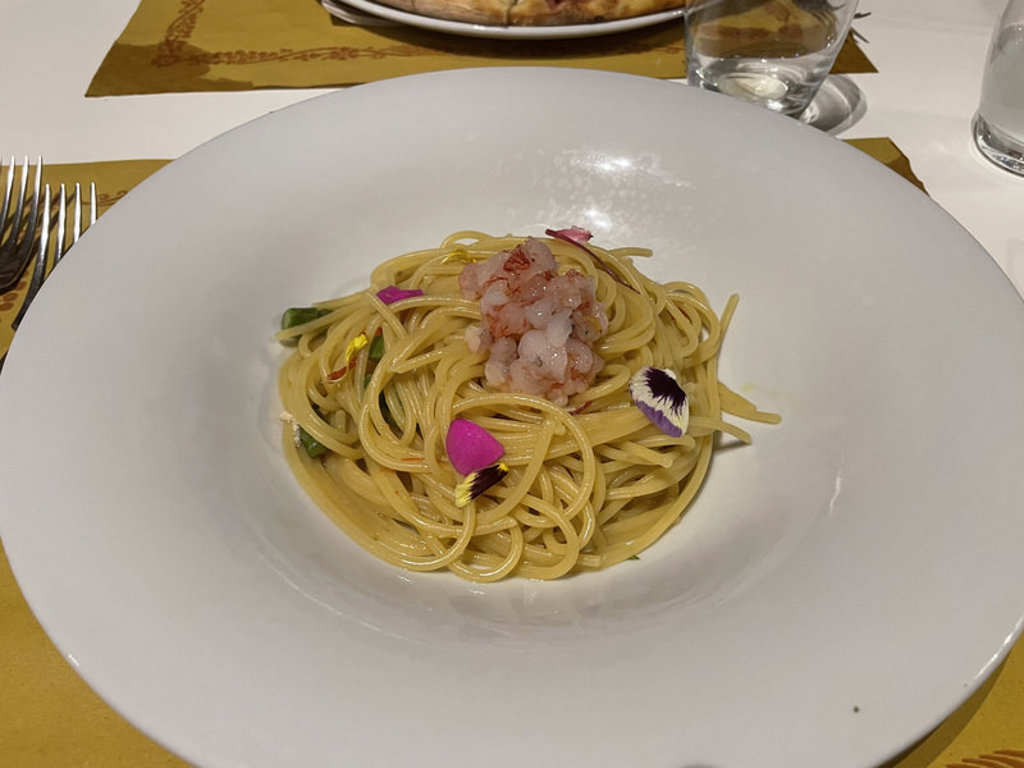 Bord spaghetti met garnalen en eetbare bloemen, typisch Zuid-Italiaanse keuken tijdens de groepsrondreis.