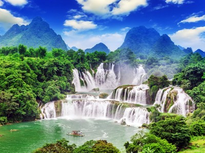 Ban Gioc-watervallen aan de China-Vietnamgrens, met groene karstbergen en een boot op de rivier.