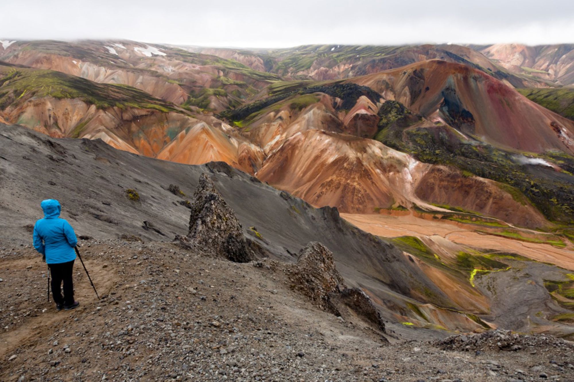 Wandelaar kijkt uit over de kleurrijke rhyolietbergen van Landmannalaugar in IJsland.