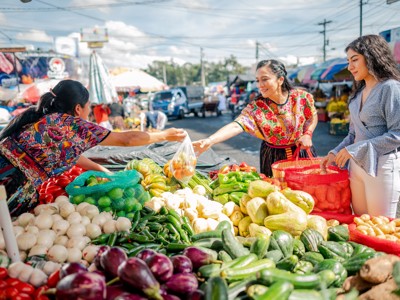 Vrouwen kopen verse groenten op een kleurrijke markt in Guatemala tijdens de Route Guatemala, 21 dagen.