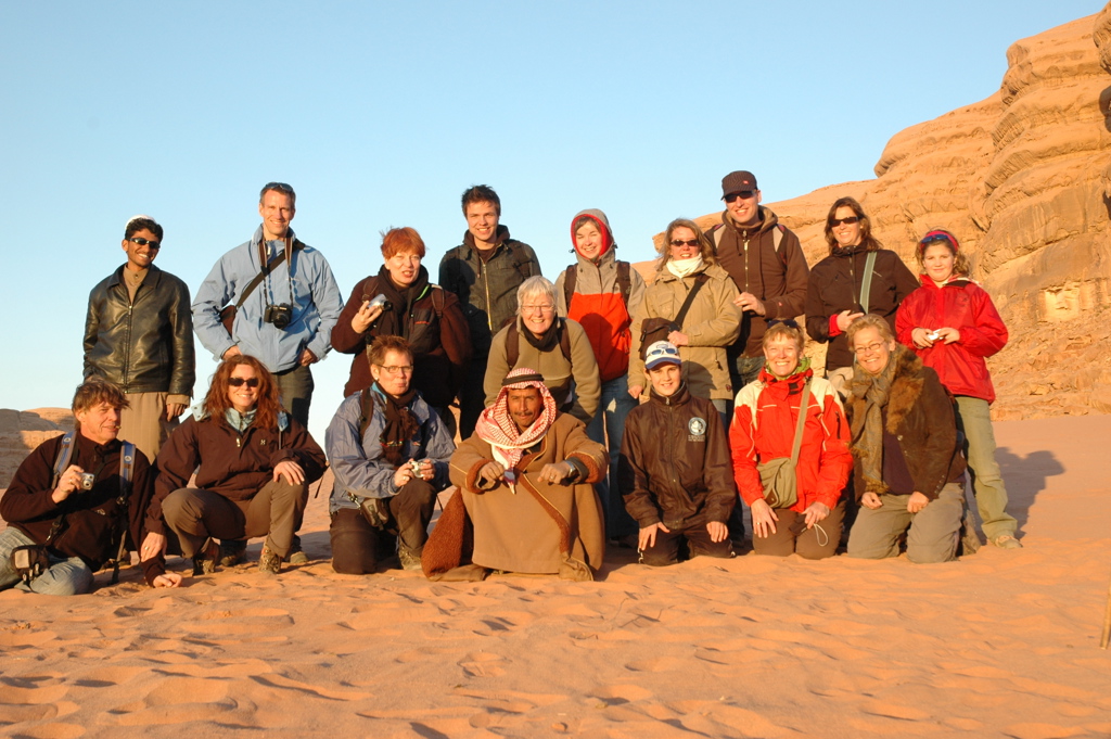 Groepsfoto van reizigers tijdens een groepsrondreis in Jordanië, in de woestijn bij rotsformaties.