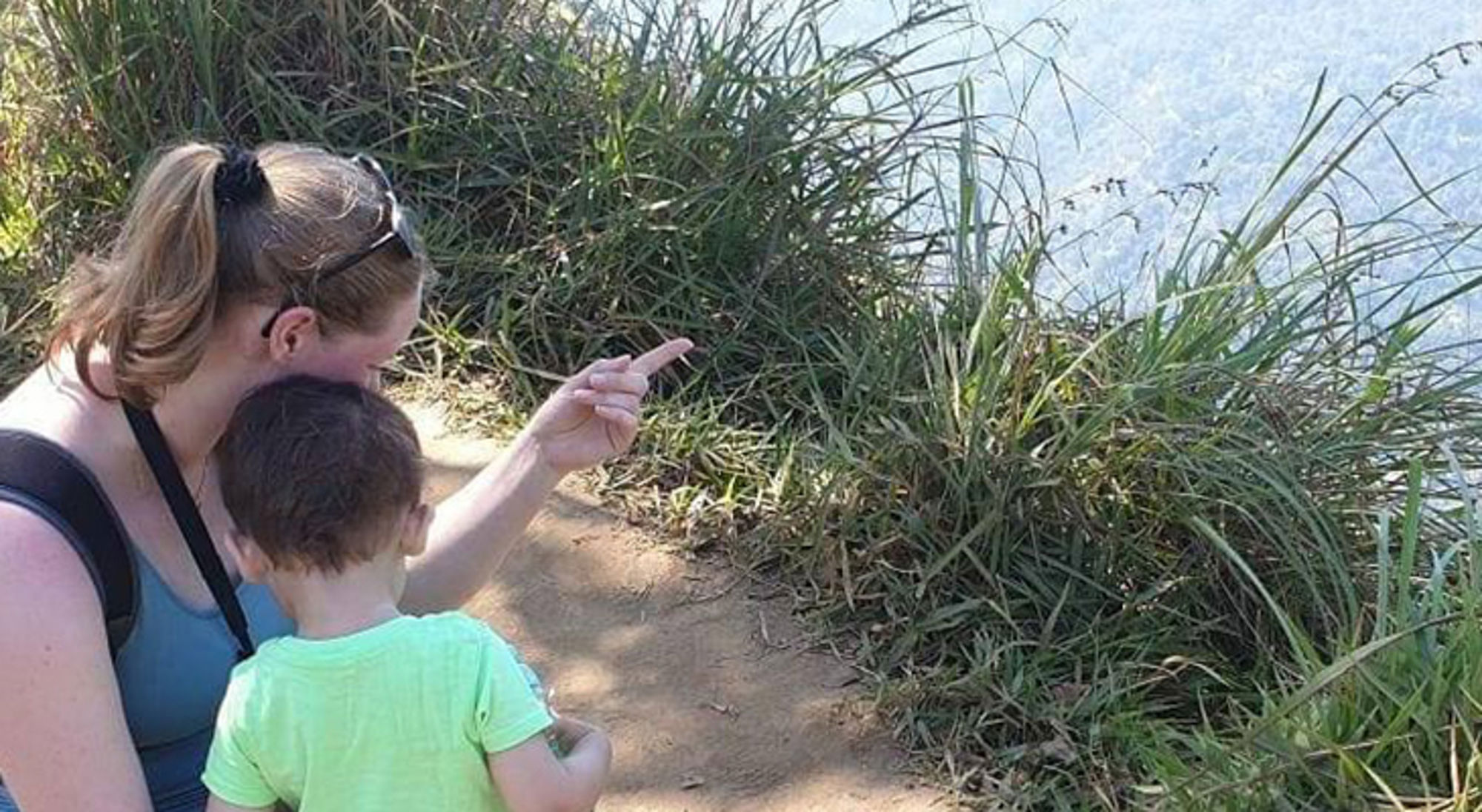 Julia in Sri Lanka Moeder en kind kijken naar water vanaf een zandpad met duingras.