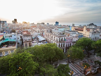 Uitzicht over Havana met historische gebouwen en boomrijke boulevard bij zonsondergang.