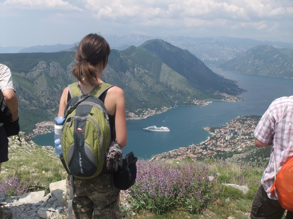 Wandelaar met rugzak kijkt uit over de Baai van Kotor in Montenegro tijdens 22-35ers reis Balkan.