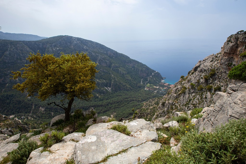 Uitzicht vanaf een bergpad over de Turquoise Kust in Turkije, met rotsen, groen en de azuurblauwe zee.