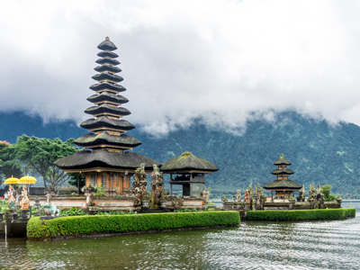 Ulun Danu Beratan-tempel aan het Bratanmeer op Bali, met bergen en wolken op de achtergrond.