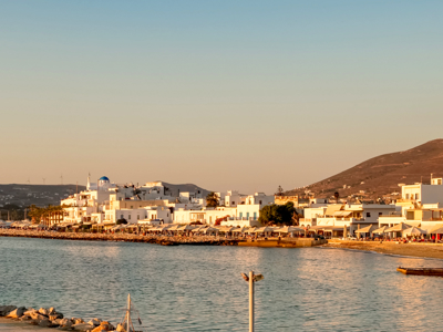 Kustplaats op Paros met witte huizen en promenade aan zee in avondlicht tijdens de wandelvakantie Naxos, Santorini en Paros.