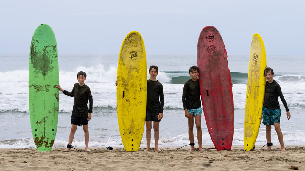 Kinderen met surfplanken op het strand tijdens een familiereis in Costa Rica.