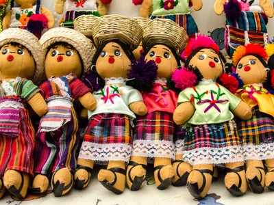 Handgemaakte poppen in kleurrijke traditionele kleding op een markt langs de Route Ruta Maya.