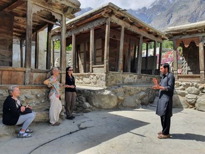 Reizigers luisteren naar uitleg bij houten huisjes in Hunza, tijdens de route Pakistan - Baltistan & Hunza.